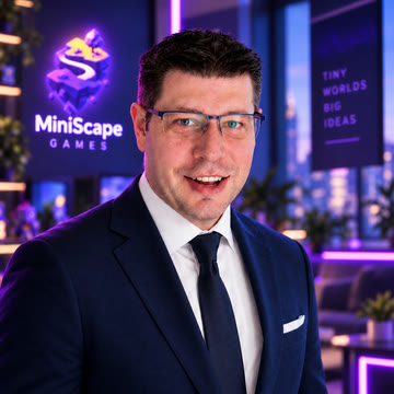Michael Braam, in front of the MiniScape Games logo on the studio wall.